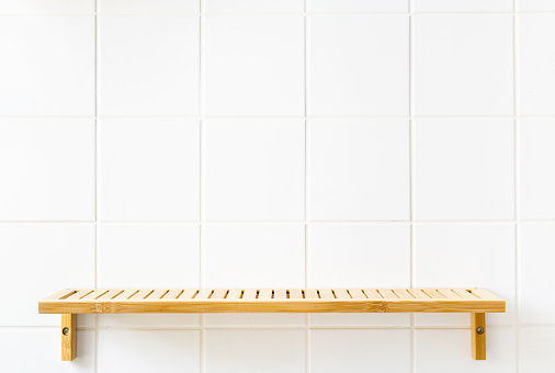 Empty bamboo shelf on white tile wall in bathroom. Copy space. Minimal composition. Zero waste and sustainable life style