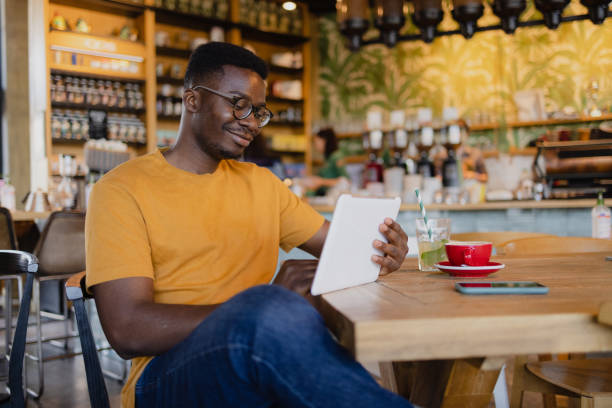 istock Happy African American man using a digital tablet computer in a coffee shop 1335062150