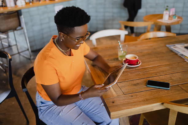 istock High angle view of a happy African American woman using a digital tablet computer in a coffee shop 1335062419
