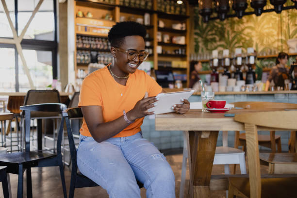 istock Happy African American woman using a digital tablet computer in a coffee shop 1335062421