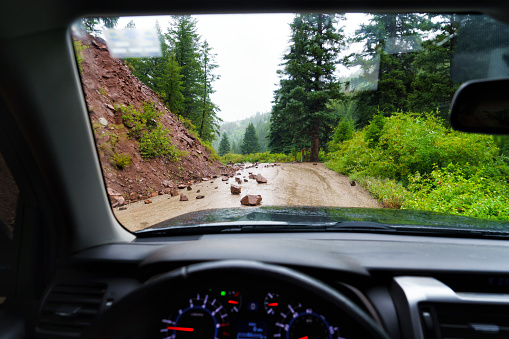 Fresh Rockslide Debris on Road through Windshield View POV - Narroe steep red rock canyon letting loose large rocks and boulder that spilled onto dirt road blocking way.