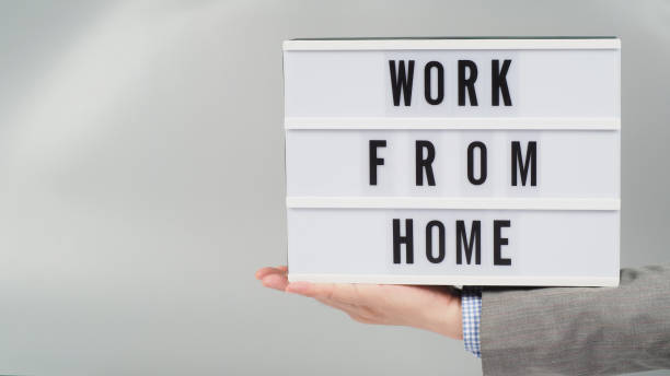 istock Hands is holding light box with word work from home on gray background.Wear grey suit.businessman concept. 1335064376