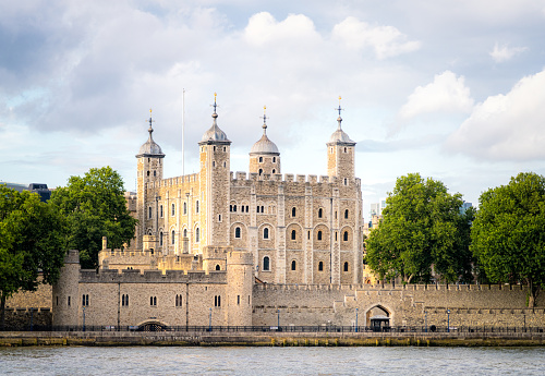 A view of the Tower of London from across the river, with the White Tower illuminated by evening light.