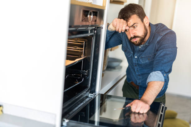 istock Tired young man fixing an oven at home. 1335066788