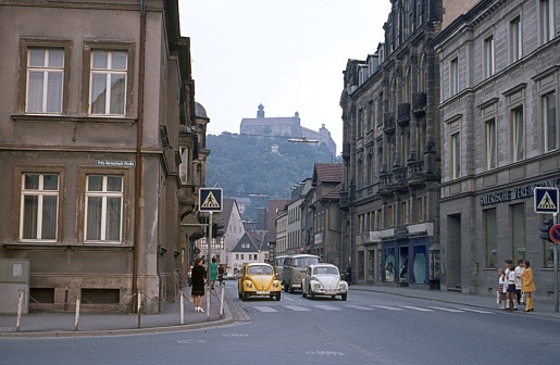 Kulbach, Upper Franconia, Bavaria, Germany, 1972. Street scene with passers-by, buildings and vehicles in the Franconian town of Kulmbach. In the background the Plassenburg (castle).
