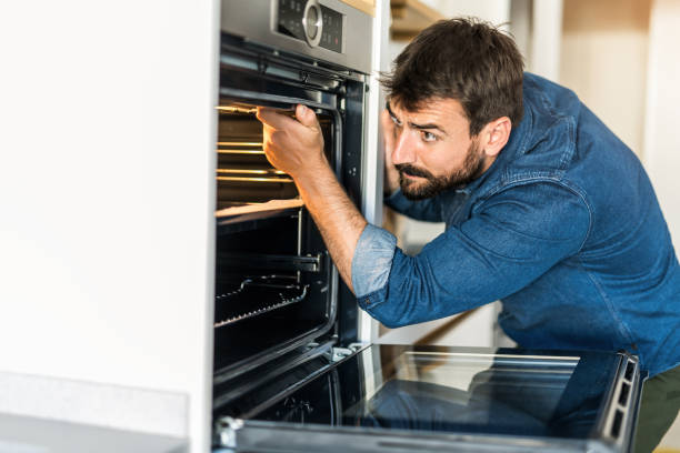 istock Young man fixing an oven at home. 1335066893
