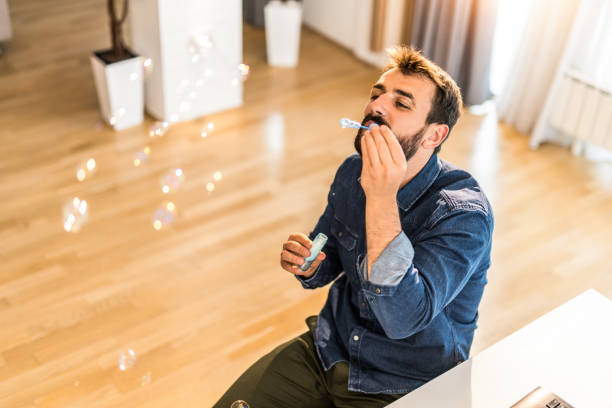 istock Happy young man blowing bubbles at home. 1335067997