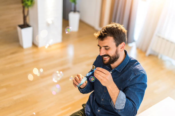 istock Happy young man blowing bubbles at home. 1335068021