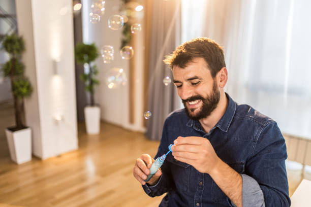 istock Happy young man blowing bubbles at home. 1335068098