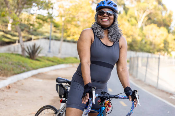 mujer negra senior montando bicicleta - casco de deportes fotos fotografías e imágenes de stock