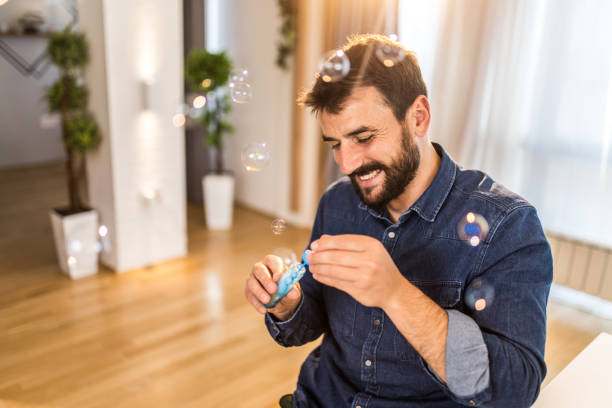 istock Happy young man blowing bubbles at home. 1335069008