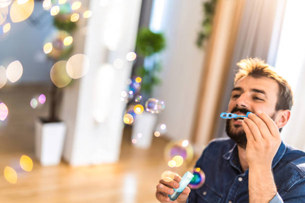 istock Happy young man blowing bubbles at home. 1335069053