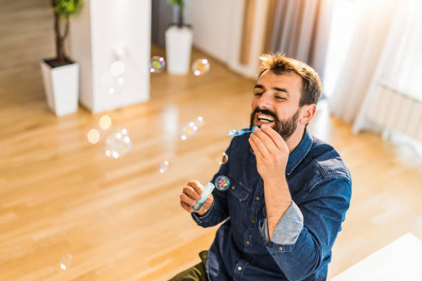 istock Happy young man blowing bubbles at home. 1335070102