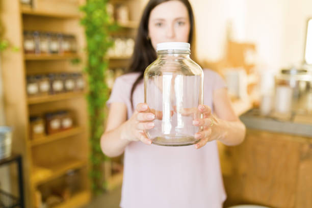 Ready to do plastic-free shopping. Young woman coming into a sustainable bulk shop with her container to buy dry food and nuts