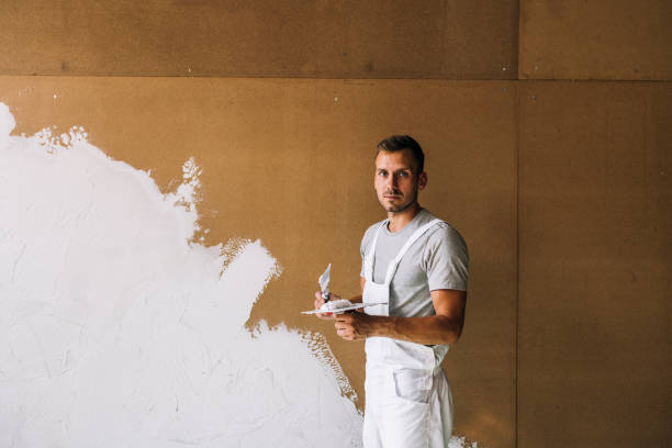 portrait of a serious young man plastering wall in his workshop - plaster plasterer wall repairing imagens e fotografias de stock