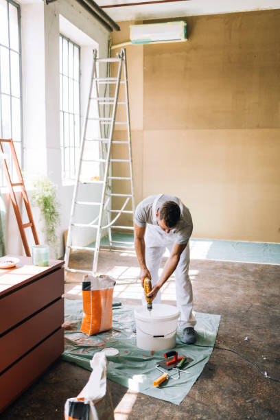 istock Man Mixing Contents of a Bucket Using Paint Mixer 1335074963