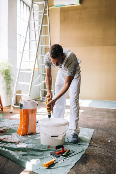 istock Man Mixing Contents of a Bucket Using Paint Mixer 1335074965