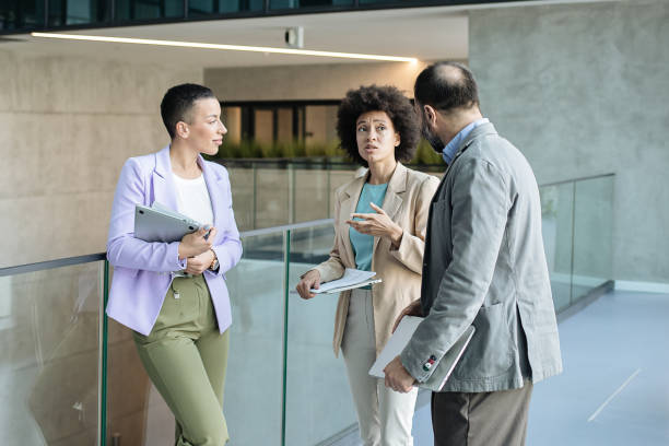 istock Businesspeople Talking to Each Other While Standing at the Corridor 1335075775