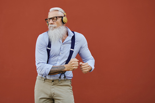 Caucasian hipster happy old man dances listening to music in the city - Seniors enjoy Caucasian hipster happy old man dances listening to music in the city - Seniors enjoy technology. focus on the face. focus on the face