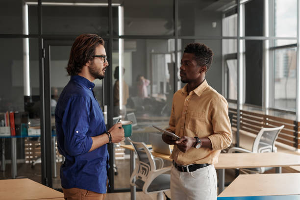 istock Young multi-ethnic managers standing in coworking space and discussing new project while one of them drinking coffee 1335079724