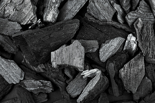 Black charcoal texture as background, top view. Close-up.