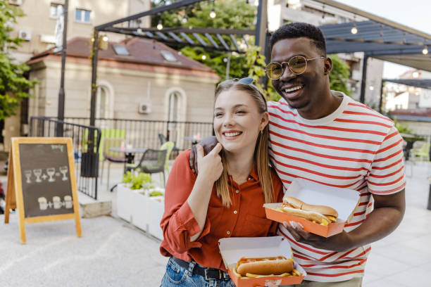 uscire e mangiare hot dog con un amico - couple blond hair social gathering women foto e immagini stock