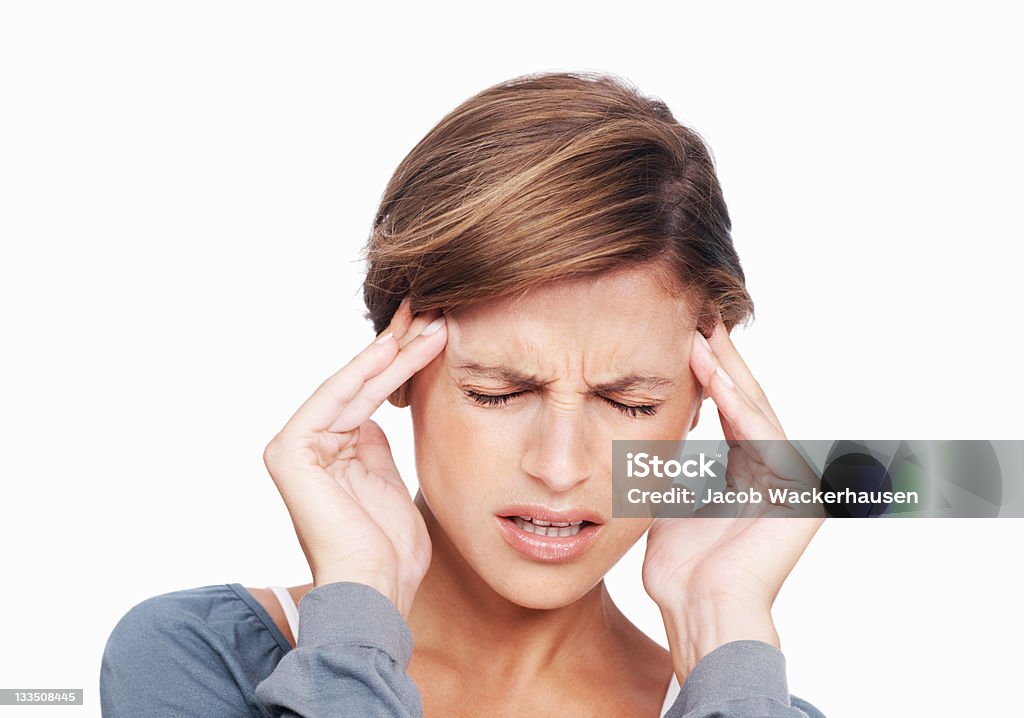 When will this pain stop? Unhappy young woman with a bad headache rubbing her temples on a white background Adult Stock Photo