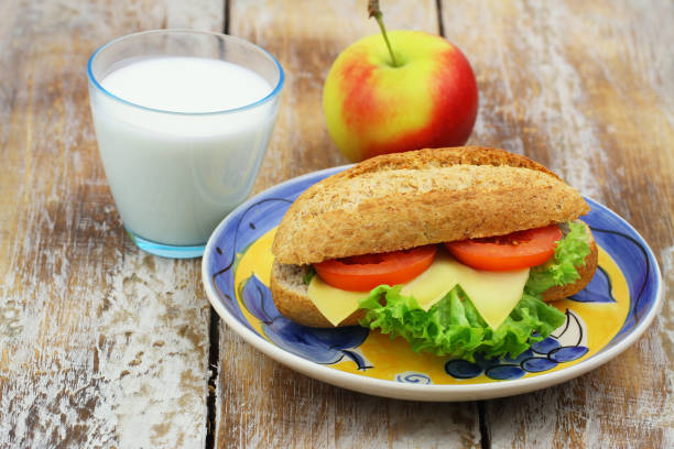 gesundes frühstück oder mittagessen: braunes käsesandwich mit salat und tomaten, apfel und glas frischer milch - lunch box lunch sandwich green stock-fotos und bilder