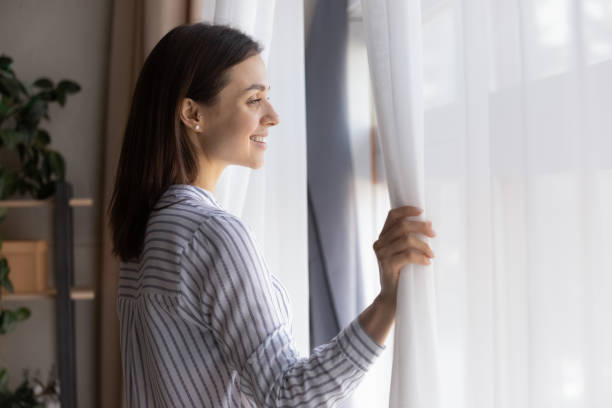 istock Smiling woman look in window thinking dreaming 1335085270