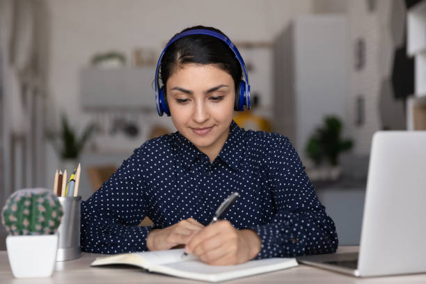 istock Smart Indian woman in earphones work online on computer 1335085285