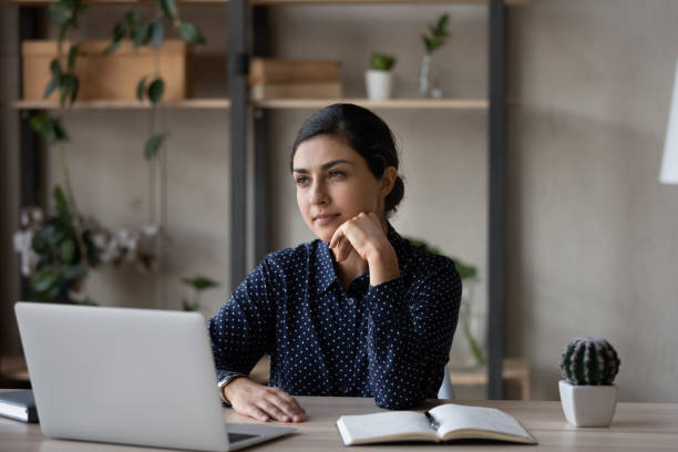 istock Pensive Indian woman work on laptop thinking 1335085317