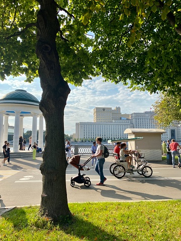 Moscow, Russia - August 15, 2021: People enjoying summer day in big city park, walking and cycling on Moskva river embankment. Gorky Park