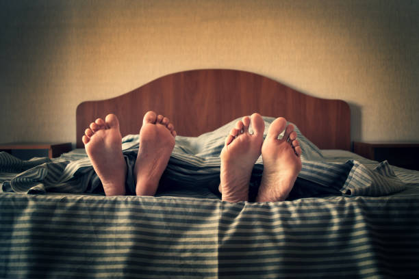 istock female and children's legs from under a striped bedspread. 1335091259