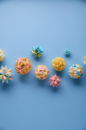 Set of multicolorÂ handmade modularÂ origami balls or Kusudama Isolated on blue background. Visual art, geometry, art of paper folding, paper crafts. Top view, close up, selective focus, copy space.
