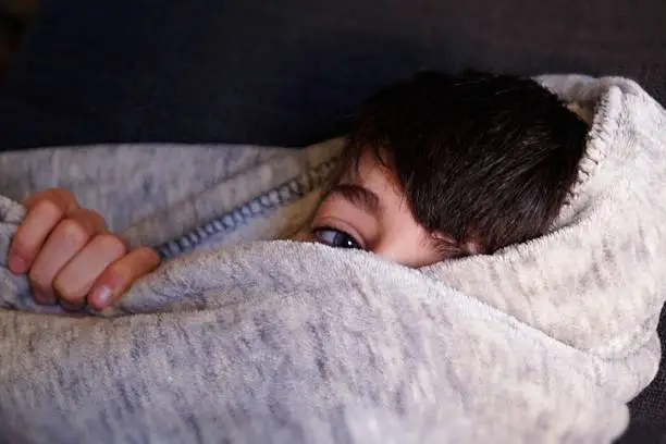 Dreaming boy, face is covered by a cozy blanket