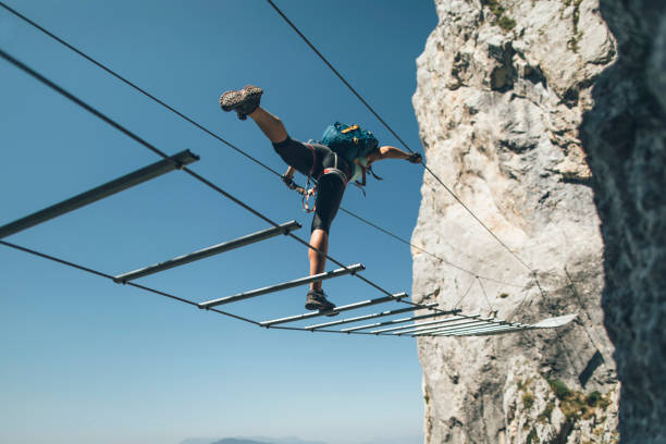 istock Climber posing on via ferrata  suspended wire bridge 1335095043