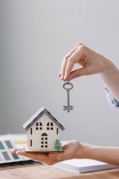 un hermoso modelo pequeño de una casa en manos de mujeres - currency house banking real estate fotografías e imágenes de stock