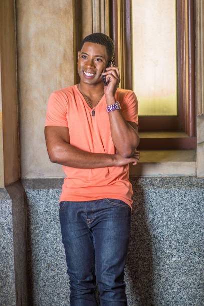 istock Young man standing inside office building, talking on cell phone 1335098192