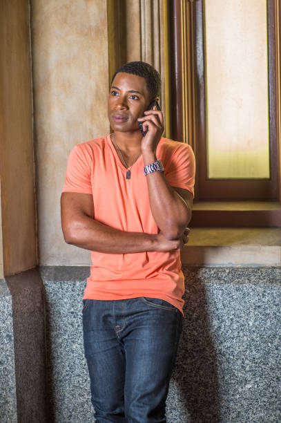 istock Young man standing inside office building, talking on cell phone 1335098193