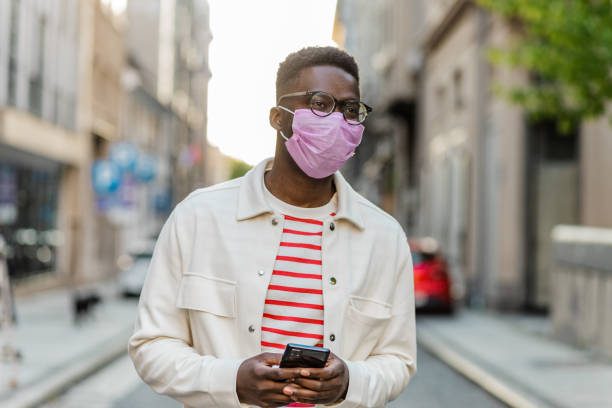 istock African-American young man walking and wearing protective face mask 1335098948