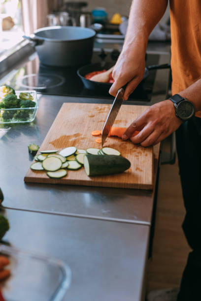 istock Anonymous Young Caucasian Man Cutting a Carrot to Pieces on a Cutting Board 1335109225