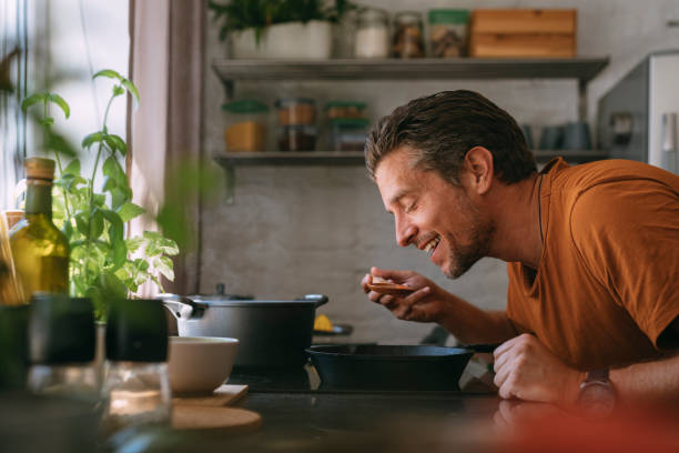 istock Handsome Young Man Tasting the Meal in a Kitchen with a Wooden Spoon 1335109265