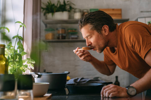 istock Handsome Young Man Tasting the Meal in a Kitchen 1335109269