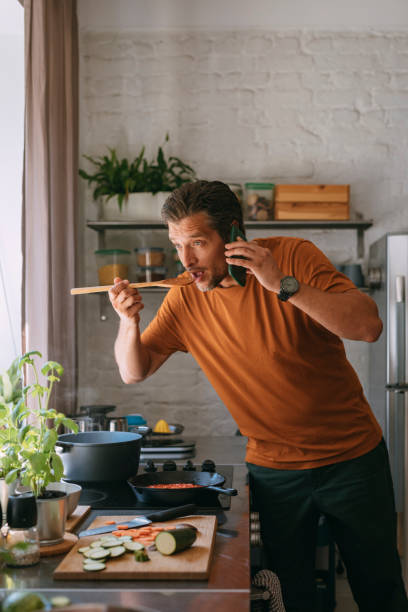 istock Handsome Young Man Having a Phone Call while Tasting a Meal at Home 1335109273