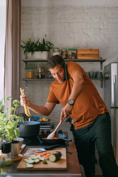 istock Handsome Young Man Having a Phone Call while Preparing a Meal at Home 1335109282