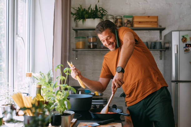 istock Handsome Young Man Having a Phone Call while Preparing a Meal at Home 1335109283
