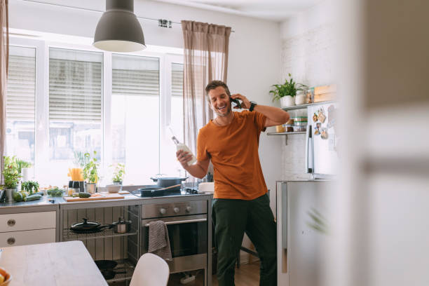 istock Happy Handsome Man Standing in the Kitchen While Having a Phone Call and Holding a Bottle 1335109290