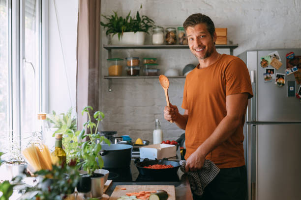 istock Handsome Happy Man Holding a Wooden Spoon While Preparing a Meal at Home 1335109295