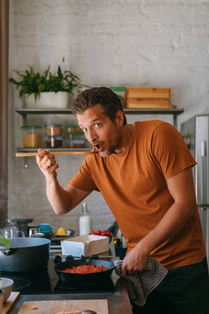 istock Handsome Happy Man Holding a Wooden Spoon While Preparing a Meal at Home 1335109297