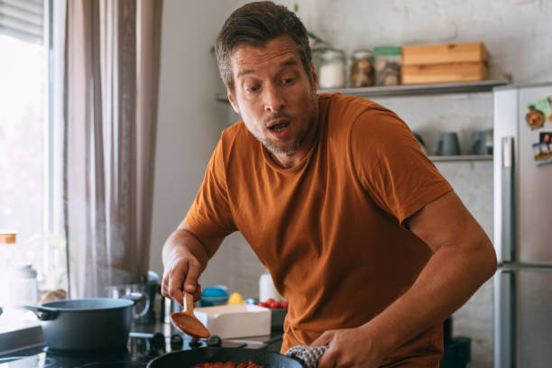 istock Handsome Man Looking Surprise while Holding a Hot Pan and a Wooden Spoon 1335109302